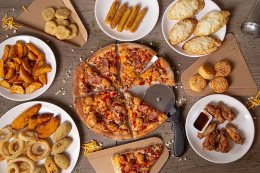 An overhead shot a restaurant table with sliced pizza surrounded by delicious snacks and appetizers