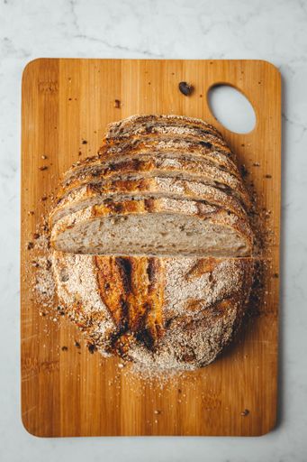 A vertical shot of fresh sourdough bread on wooden chopping board