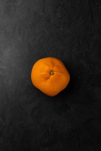 A vertical shot of orange fruit photographed against a black background, from the top.With copy space.