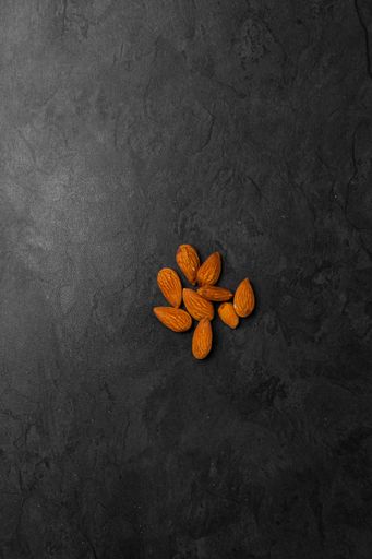 A vertical top view of pile of fresh almond nuts isolated on a black background