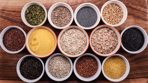 A closeup of the various spices and seeds in the bowls on a wooden surface. Top view.