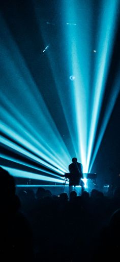A vertical shot of an artist giving a concert surrounded by blue neon lights