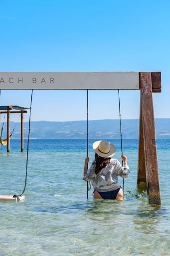 A rear view of a woman swinging on a swing in the sea in Omis, Croatia