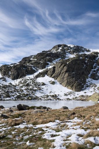 A beautiful scenery of a snow-covered landscape with rocky cliffs under a cloudy sky