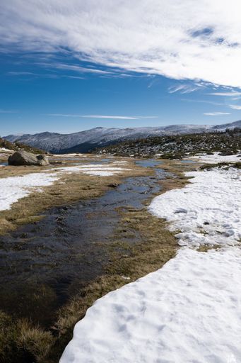 A beautiful scenery of a snow-covered landscape with rocky cliffs under a cloudy sky