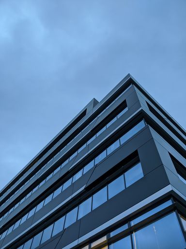 A vertical low angle shot of a glass modern building under a blue sky