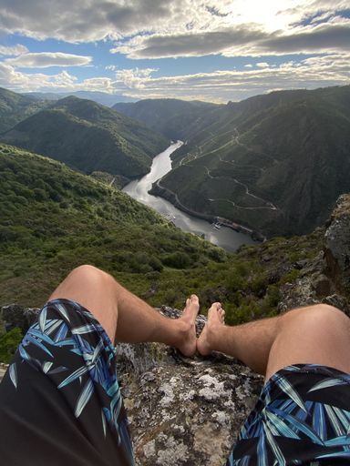 A vertical shot of a man sitting on a stone in the Sil Canyon in Spain