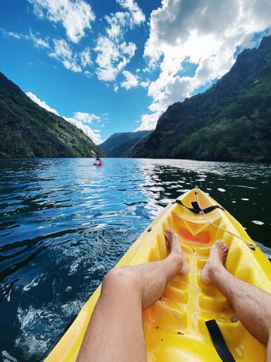 A vertical shot of a man on a yellow boat in Sil Canyon in Spain