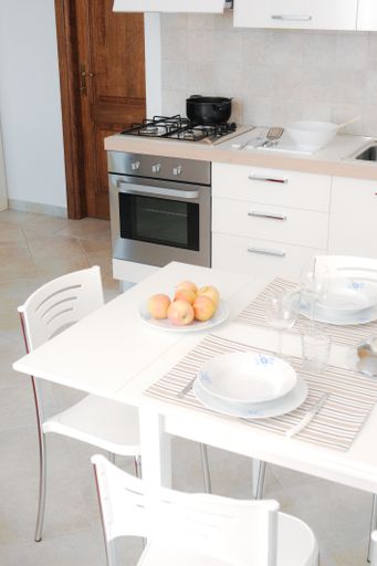 A vertical shot of the interior of a kitchen with a white table and a counter under the lights