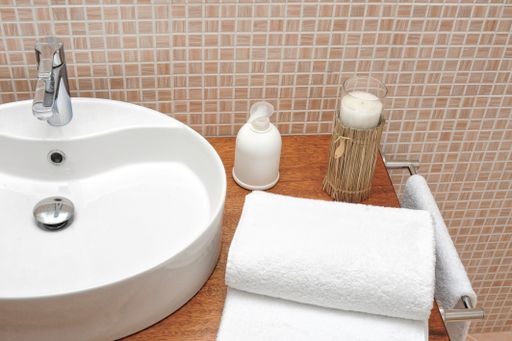 A high angle view of a white sink with folded towels and bottles near it in the bathroom