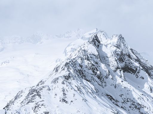 A beautiful wide shot of mountains covered in snow under a foggy sky