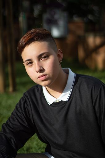 A vertical portrait of an attractive Hispanic female with a short haircut