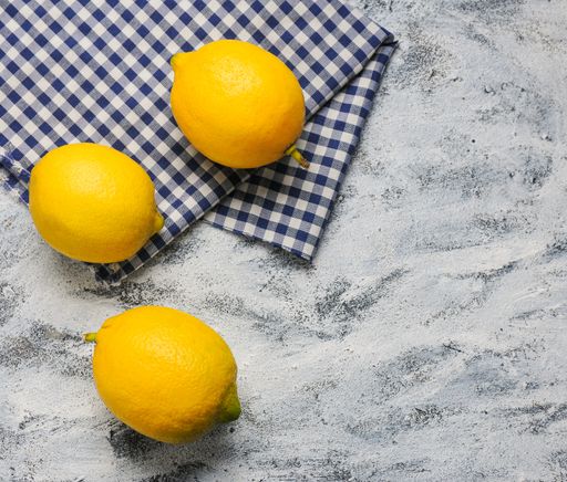An overhead shot of three lemons on the table with a towel on it