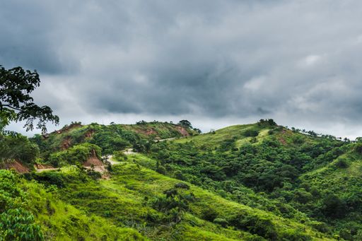 A beautiful scenery of green hills with cloudy sky in the background