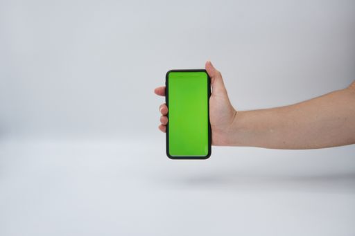 A person holding a smartphone with a green wallpaper vertically isolated on a grey background