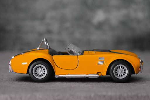 A miniature yellow toy car on a gray background