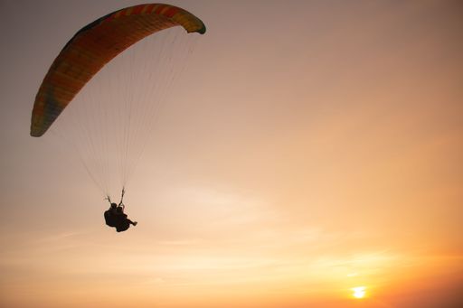 Tandem paragliding closeup over the ocean while golden sunset at Parangtritis beach on Java island in Indonesia