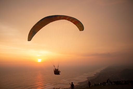 Tandem paragliding closeup over the ocean and beach while golden sunset at Parangtritis on Java island in Indonesia