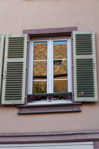A low-angle shot of an old-styled building window in the streets of Colmar, France