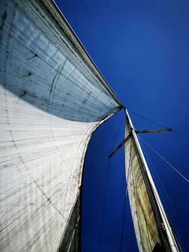 A vertical shot of the yacht sailboat and mast under the blue sky