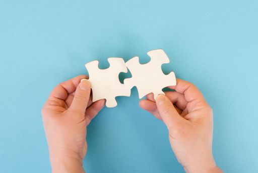 Holding two pieces of a puzzle in the hands, connecting together as a team, solving a problem, strategy and communication concept