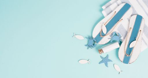 Blue colored summer and holiday background, flip flops, sea stars and a glass bootle with copy space, travel and tourism concept