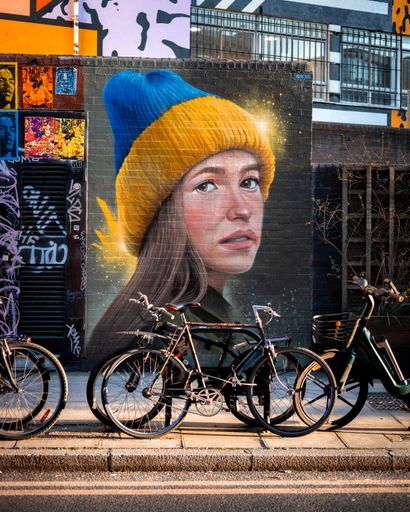 A vertical shot of a Ukraine themed street art portrait of a girl in London