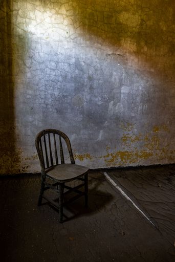 A vertical shot of an old wooden chair in an abandoned house
