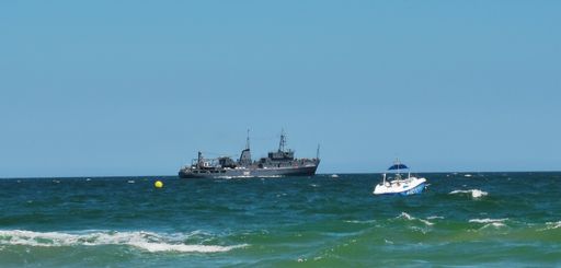A beautiful shot of the blue sea with a cruise ship and a small boat floating under the sunny weather