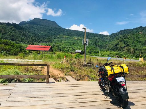 A pulsar 200NS motorcycle on a wooden deck with forested mountains in the background