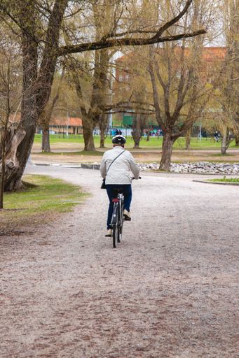 A vertical shot of a female riding a bicycle in the park