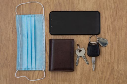 A high angel shot of a protective mask, mobile and wallet on the table