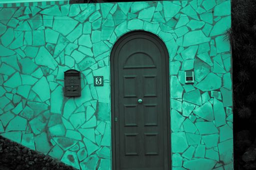 The grey door of the building with walls designed with the blue mosaic