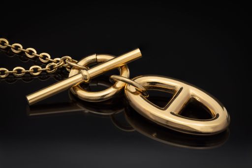 A luxury gold toned necklace reflecting in the black surface