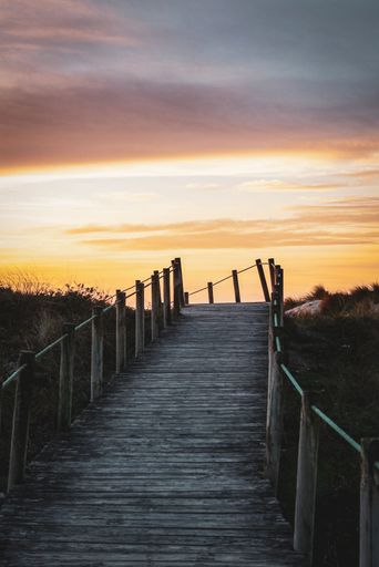A vertical of a wooden walkway under a sunset sky