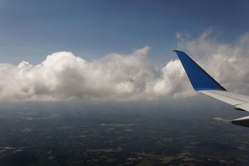 A beautiful cloudscape in the blue sky with the edge of a plane wing