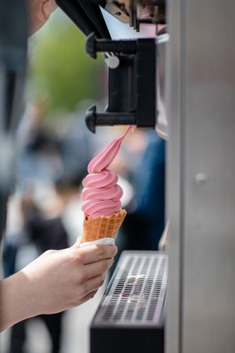 A vertical view of a person's hand holding an ice-cream from the machine