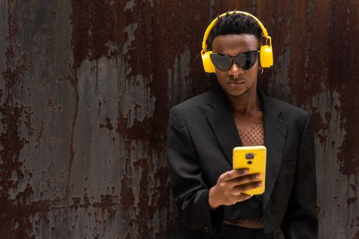 A closeup of a black ethnic man listening to music in wireless yellow headphones