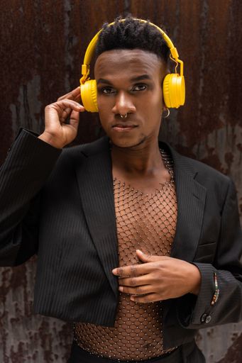A closeup of a black ethnic man listening to music in wireless yellow headphones