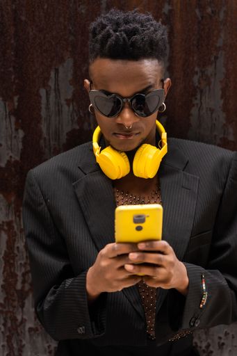 A closeup of a black ethnic man listening to music with wireless yellow headphones