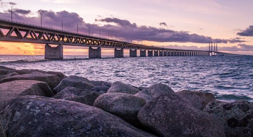 A beautiful view of the Oresundsbron bridge between Sweden and Denmark under a cloudy purple sunset sky at sunset
