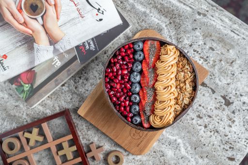 A top view of an Acai bowl with berries, peanut butter and granola
