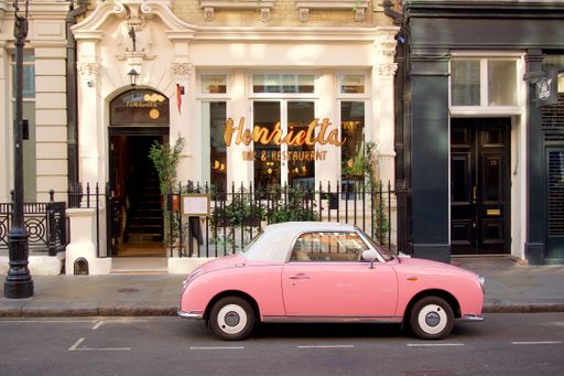 A beautiful shot of a Pink Nissan Figaro car in the street in Henrietta St, London