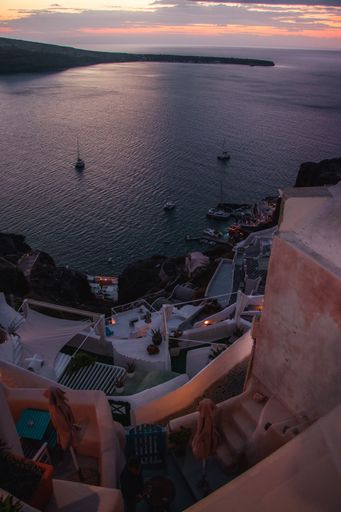 A vertical shot of a gorgeous sunset viewed from the balcony of a small house in Oia, Greece