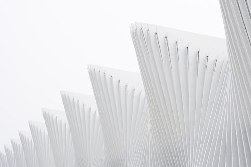 A horizontal shot abstract buildings with white metallic ribs and glass windows. Perfect for an abstract wallpaper or a background.