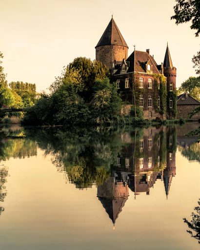 An old castle with in its reflection on the lake during sunset