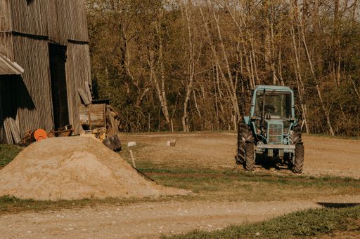 Old agricultural machinery in a farm with trees in the background