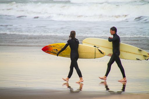 Two people walking on the beach with surfboards in Mal del Plata in Argentina