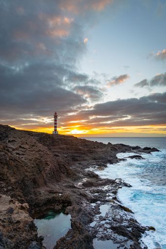 A vertical shot of Punta Sardina Lighthouse against the cloudy sky at sunset. Gran Canaria, Spain.