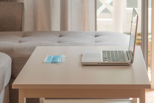 A laptop and protective mask on the table- COVID-19